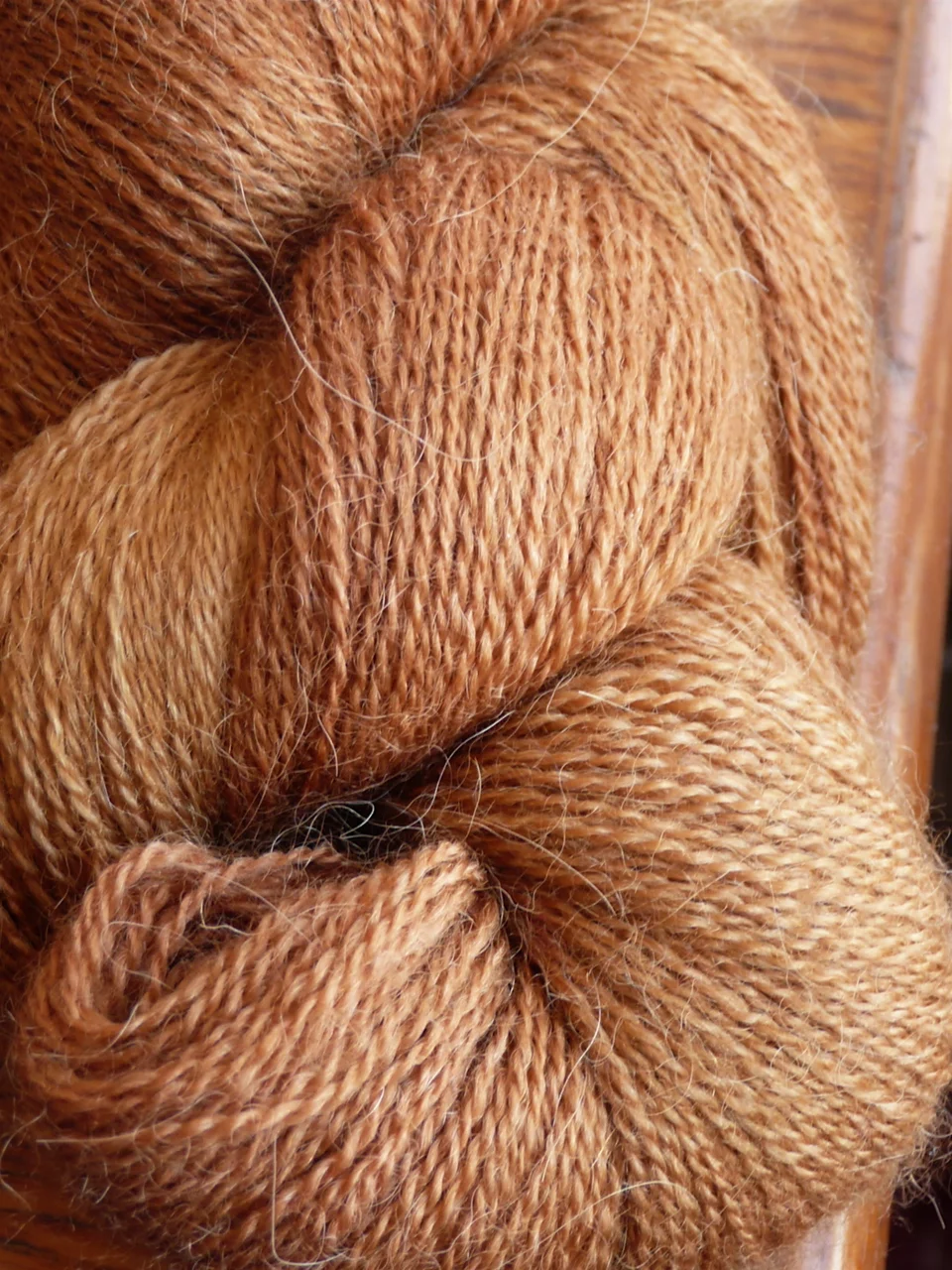 Close-up of skeins of soft light-brown yarn, fine hairs lifting away from the two-ply twist.