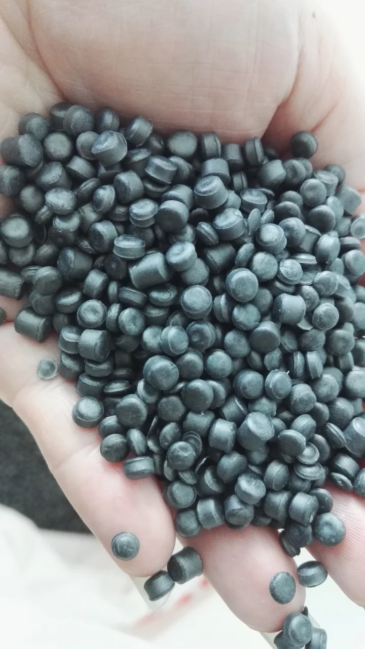 Close-up of a handful of small grey polymer granules, the cut cylinders filling the frame.