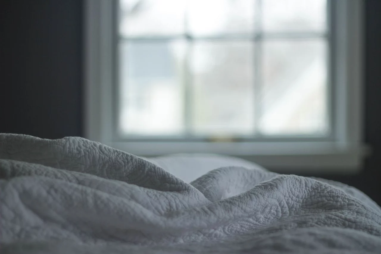 Close-up of a white quilted cloth, the stitched-through face puckering into soft raised channels.