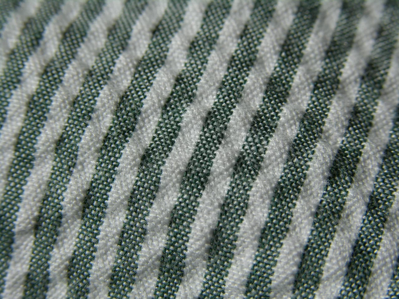 Close-up of green and white seersucker, the striped bands alternating between flat and puckered cloth.