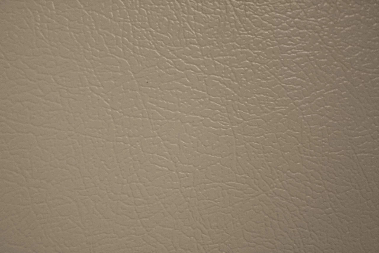 Macro close-up of a beige faux-leather surface, the fine embossed grain running evenly across the frame.